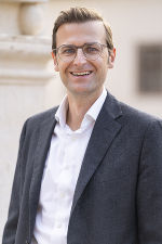 Auf dem Bild ist Herr Matzer Clemens in einem schwarzen Sakko mit weißem Hemd zu sehen